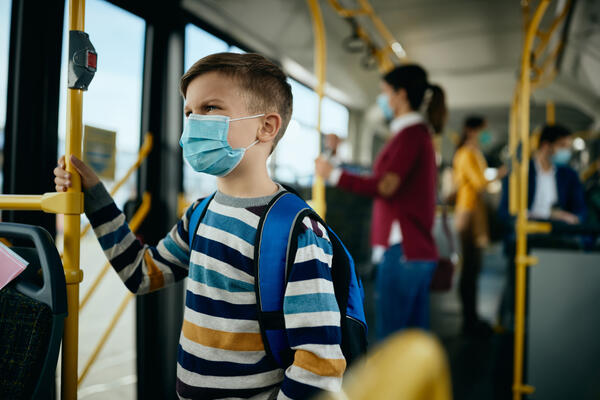 Bild vergr&ouml;&szlig;ern: Auf dem Bild sieht man ein Kind in einem &ouml;ffentlichen Bus mit Mundschutz.