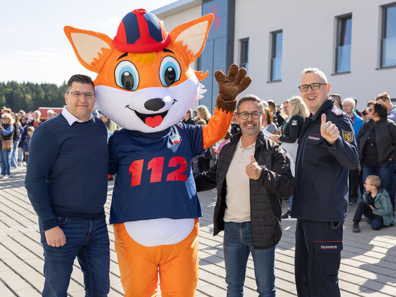Landrat Thomas Hennig, S&ouml;ren Voigt und Daniel L&ouml;wenhagen umarmen einen gro&szlig;en Feuerfuchs.