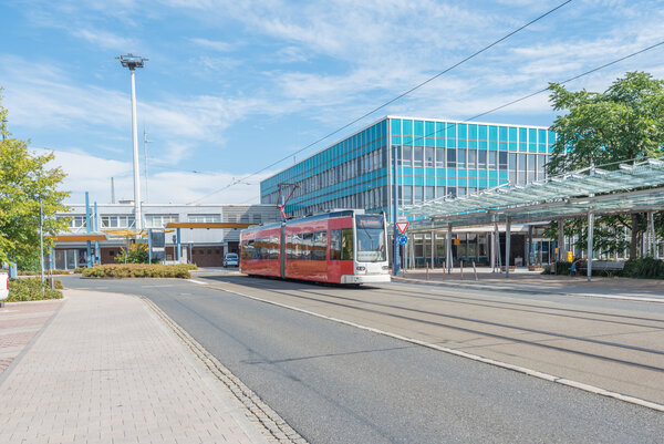 Bild vergr&ouml;&szlig;ern: Das Bild zeigt eine Plauener Stra�enbahn. Die rote Bahn f�hrt vor dem typischen blauen Geb�ude des oberen Bahnhofs in Plauen.