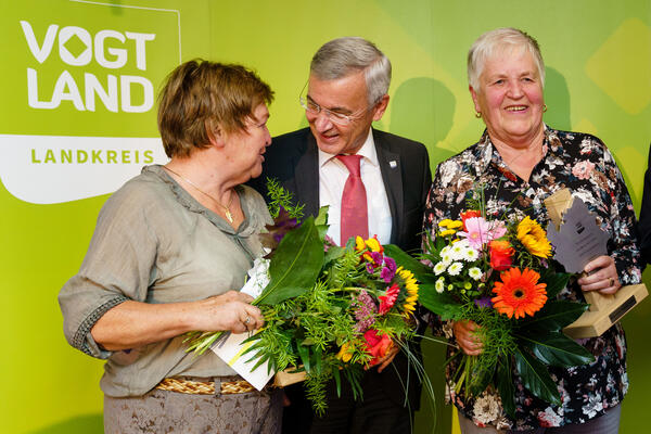 Bild vergr&ouml;&szlig;ern: Landrat Rolf Keil &uuml;berreicht zur Ehrenamtsgala 2019 zu Ehrenden einen Blumenstrauss auf der B&uuml;hne.
