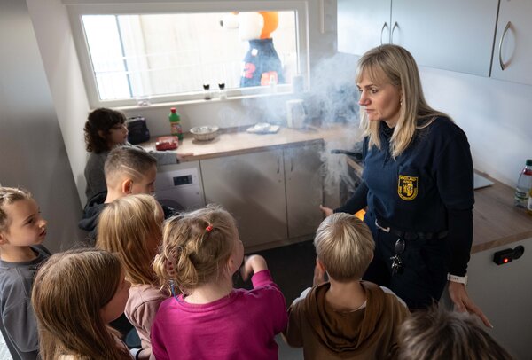 Bild vergr&ouml;&szlig;ern: Das Bild zeigt Anja Haymann, die vor Kindern erkl&auml;rt, wie man sich in einer verrauchten K&uuml;che richtig verh&auml;lt