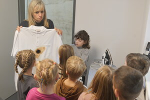 Bild vergr&ouml;&szlig;ern: Auf dem Bild sieht man Anja Haymann, die ein verbranntes T-Shirt hochh&auml;lt. ES hat ein Loch von einem B&uuml;geleisen