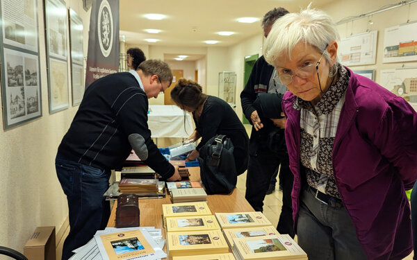 Bild vergr&ouml;&szlig;ern: Das Bild zeigt einen Teil der interessierten Besucher im historischen Archiv auf Schloss Voigtsberg. Hier stehen sie an einem Stand, an dem man Literatur kaufen konnte.