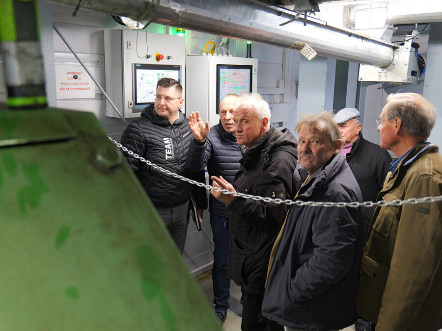 Die Besuchergruppe schaut auf eine alte Maschine. Es ist eine &Ouml;lpresse von 1992.