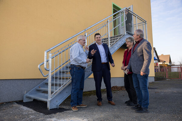 Bild vergr&ouml;&szlig;ern: Vor der neuen Fluchttreppe: Landrat Thomas Hennig im Gespr&auml;ch mit der Kita-Leiterin, dem B&uuml;rgermeister und dem Ortsvorsteher.