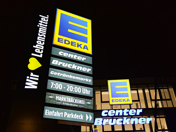 Bild vergr&ouml;&szlig;ern: Das Eingangs- und Stra�enschild eines Edekamarktes. Es leuchtet im Dunkeln.