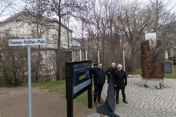 Bild vergr&ouml;&szlig;ern: Drei M�nner stehen vor dem Wendedenkmal Plauen. Sie enth�llen eine digitale Wand mit Touchdisplay.