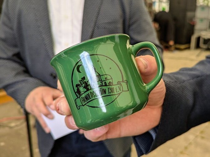 Eine gr&uuml;ne Tasse, auf der ein kleines Bild von Arnoldsgr&uuml;n zu sehen ist.