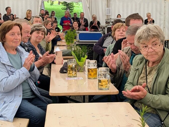 G&auml;ste sitzen auf einer Bierbank und klatschen Applaus.