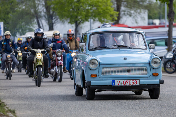 Bild vergr&ouml;&szlig;ern: Ein hellblauer Trabant gefolgt von zahlreichen Mopedfahrer auf historischen Simson-Modellen.