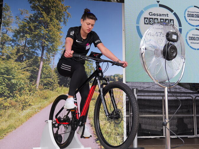 Eine Frau sitzt auf einem Rad und strampelt. Das Rad ist fest verankert.