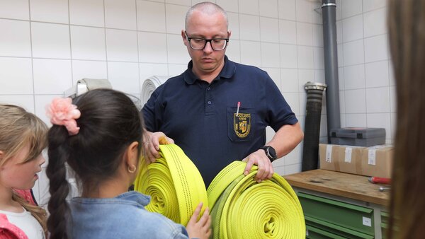 Bild vergr&ouml;&szlig;ern: Ein Mann h�lt zwei neongelbe Schl�uche hoch. Sie sind sauber.