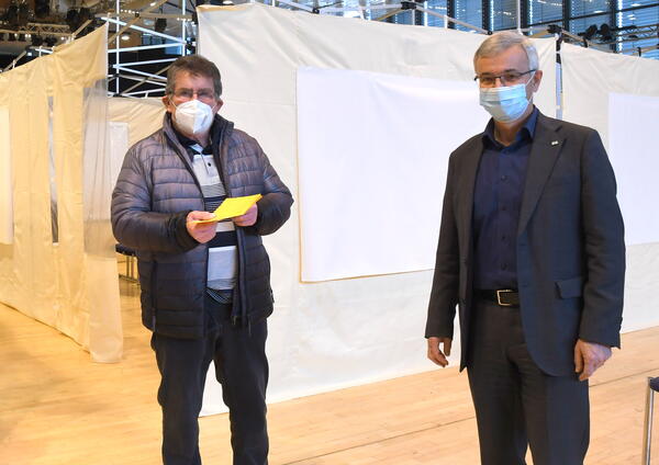 Bild vergr&ouml;&szlig;ern: Als ersten Impfling konnte Landrat Rolf Keil den Markneukirchner Klaus K&uuml;rschner begr&uuml;&szlig;en, der sich in der Musikhalle seine Auffrischungsimpfung abholte.