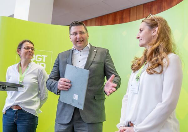 Bild vergr&ouml;&szlig;ern: Drei Personen vor der Messewand